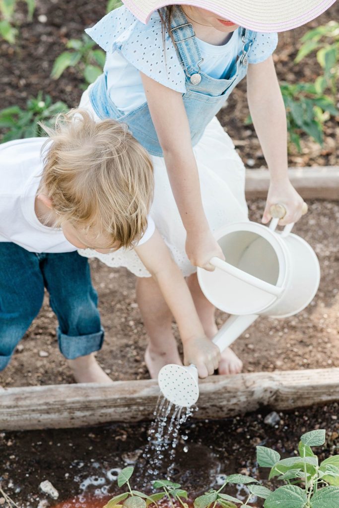 children helping to water plants in the garden