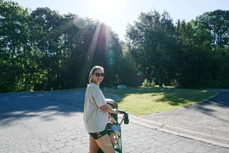 woman smiling on a walk with young children in a stroller
