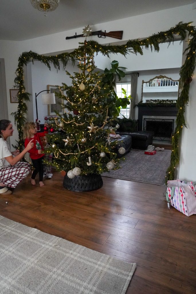 mom and children decorating christmas tree in their holiday pajamas