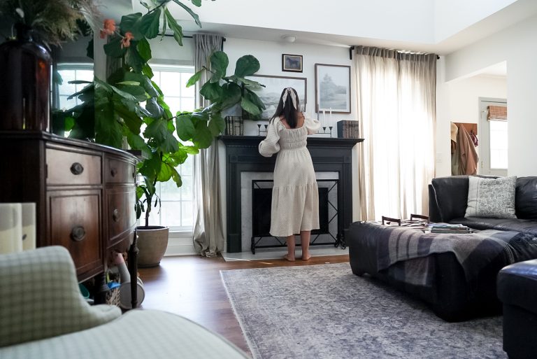 woman in flowy dress decorating her fireplace mantle