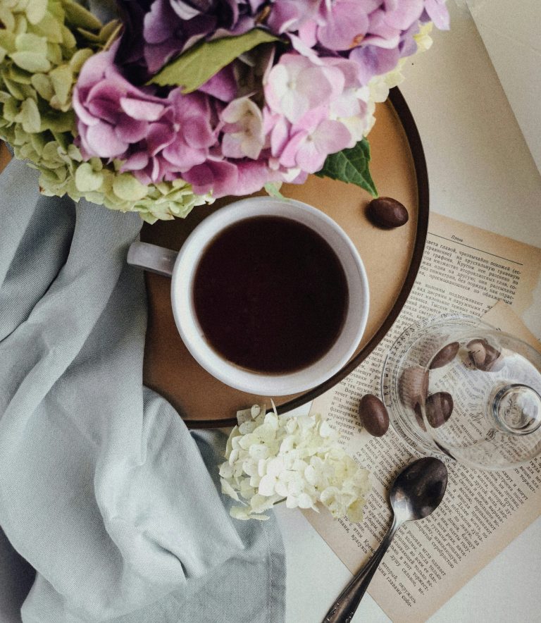 Morning cup of coffee on tray next to a bouquet of lilacs