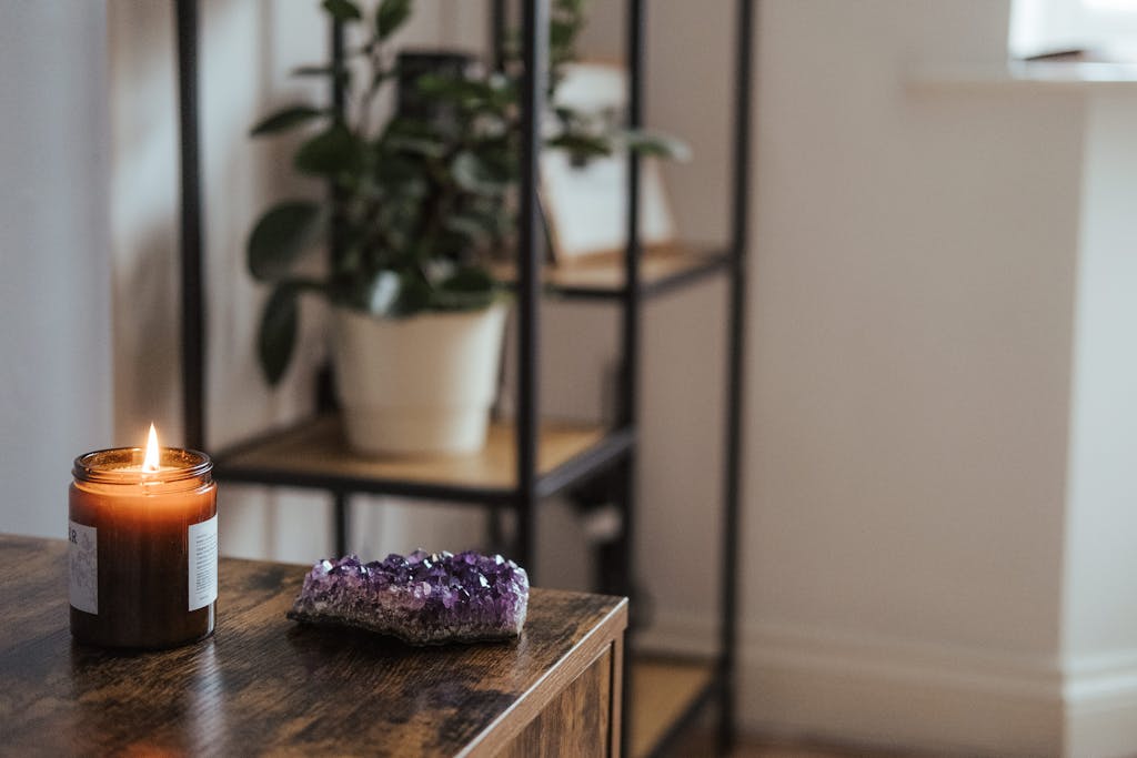 An amethyst crystal and burning candle create a cozy home atmosphere in this indoor decor scene.